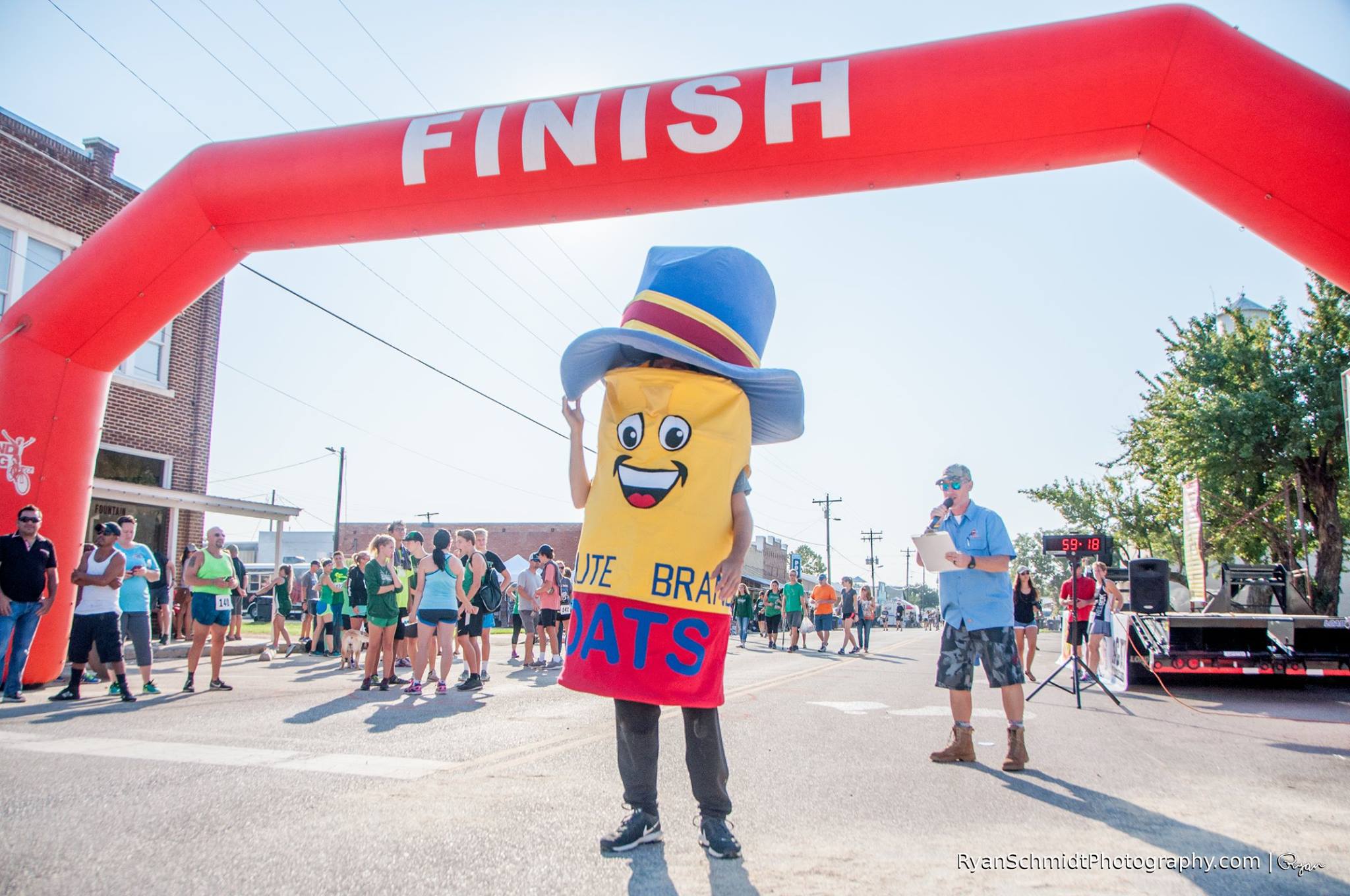 Oatie the mascot celebrating with a runner at the finish line of the Run for Your Oats Fun Run